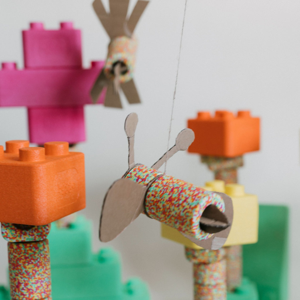 Bunte EPP-Bausteine in Pink, Orange, Gelb und Grün, kombiniert mit Bastelschablonen als Schmetterlinge und Windräder aus Kart