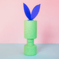Grüne EPP-Bausteine XXL gestapelt als Turm, oben blaue Papier-Osterhasenohren, rosa Hintergrund.