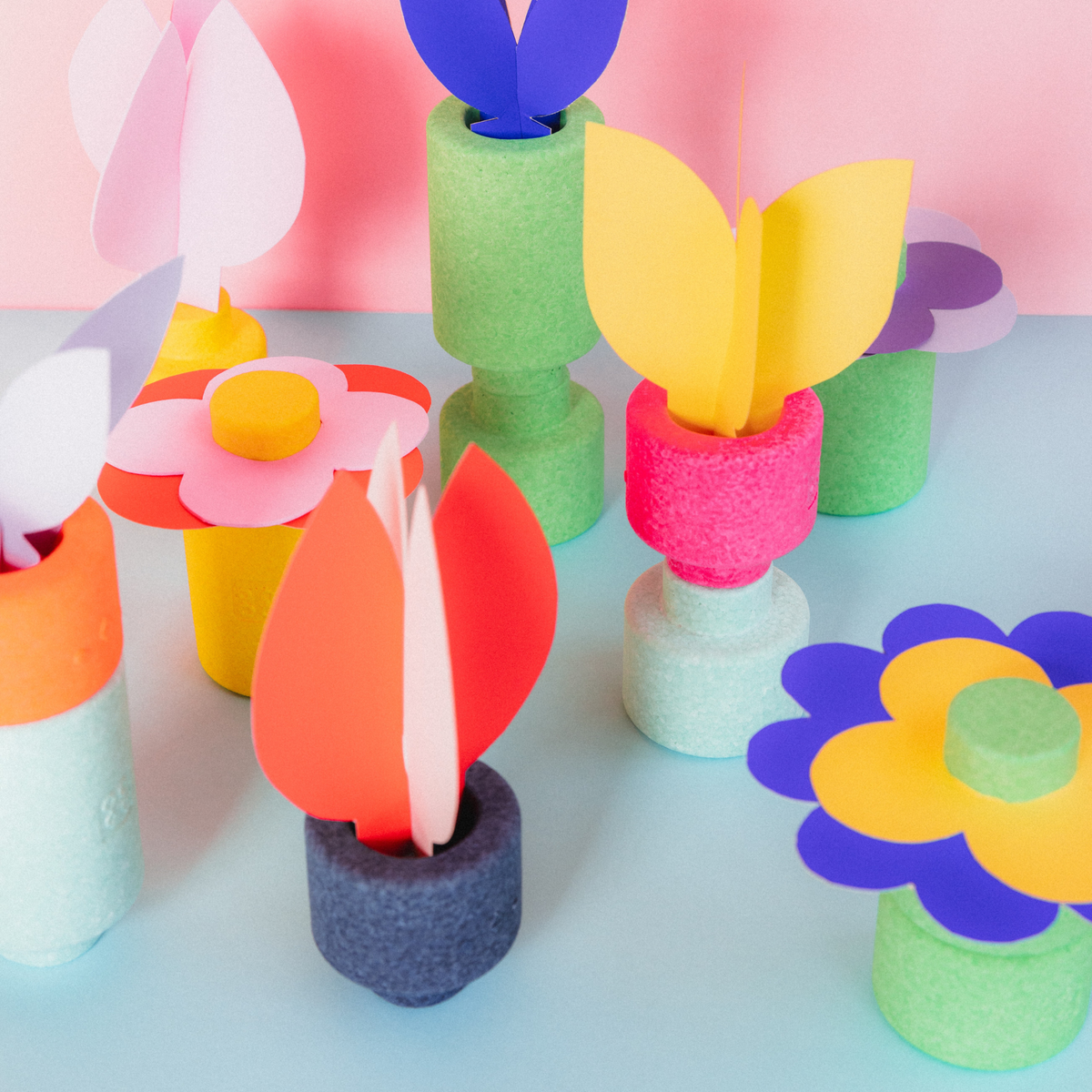 Bunte Papierblumen in EPP-Baustein-Töpfen: Tulpen, Blüten in Pink, Gelb, Blau, Rot auf hellblauem Untergrund.